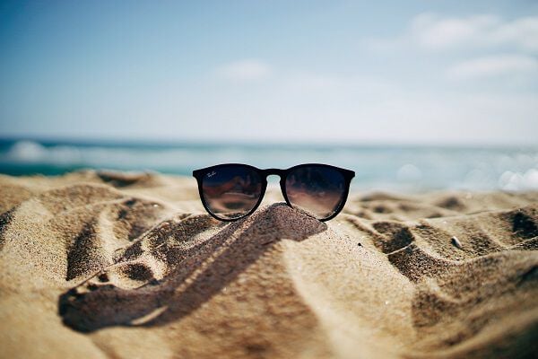 a pair of sunglasses in the sand at the beach