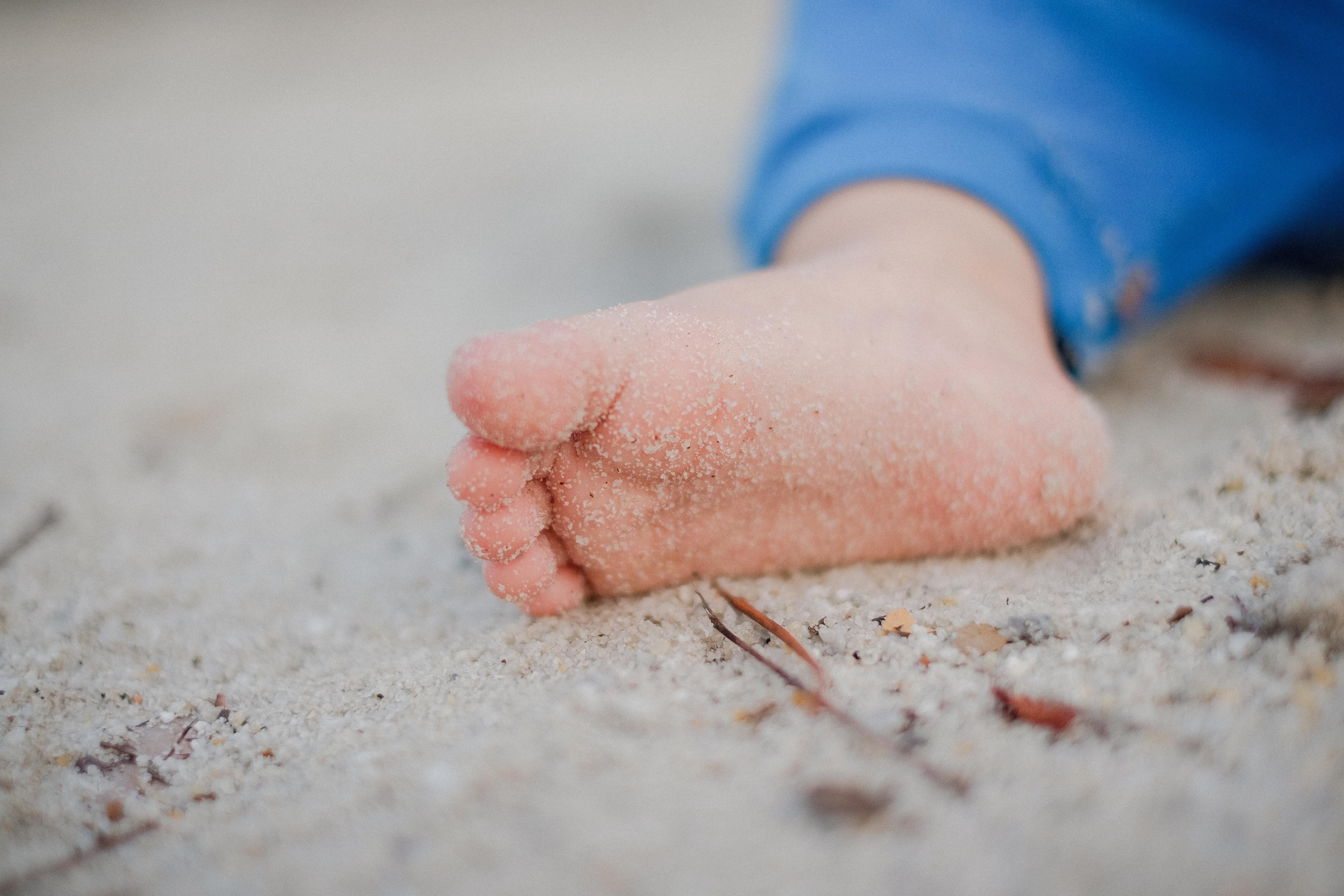a childs' foot covered in sand
